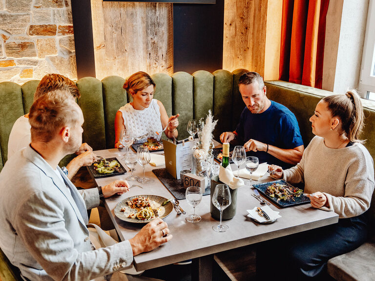 Eine Gruppe von vier Personen sitzt in einem stilvollen Restaurant und genießt eine Mahlzeit.