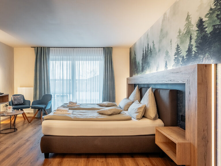Ein großes Bett mit Fernseher im Doppelzimmer Deluxe mit Gemeinschaftsgarten.