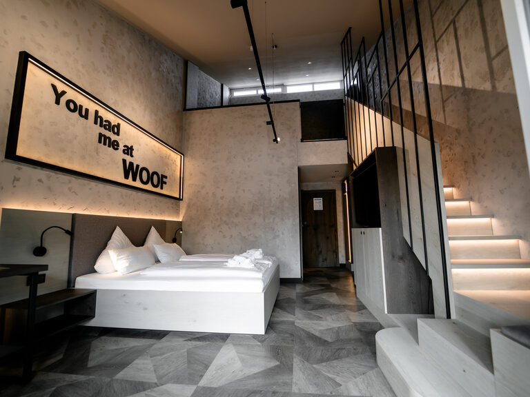 Ein stilvolles Galeriezimmer Deluxe mit großem Bett und integrierter Treppe.